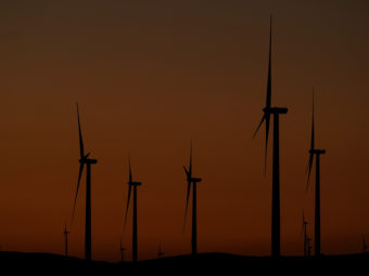 Wind turbines seen against dark red skies