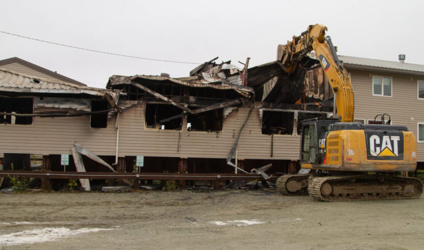 An excavator demolishing a burned-out apartment
