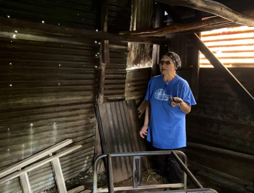 A woman stands inside an empty smokehouse