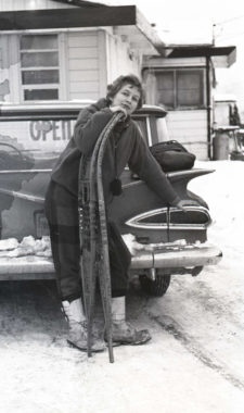 A black and white photo of a woman posing with long, willow snowsheos