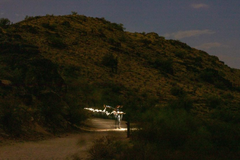 People with flashlights on a desert trail at night