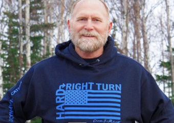 A man stands wearing a hoodie that says "hard right turn" on it