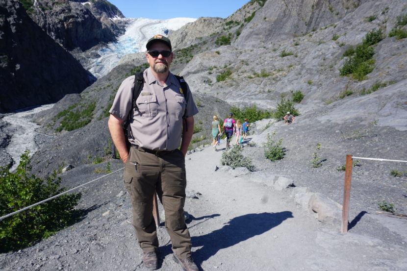 A park ranger stands on a trail to a glacier