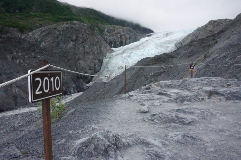 A wooden sign by a trail that says 2010, marking where the terminus of the glacier was that year. The present terminus can be seen considerably farther upslope.