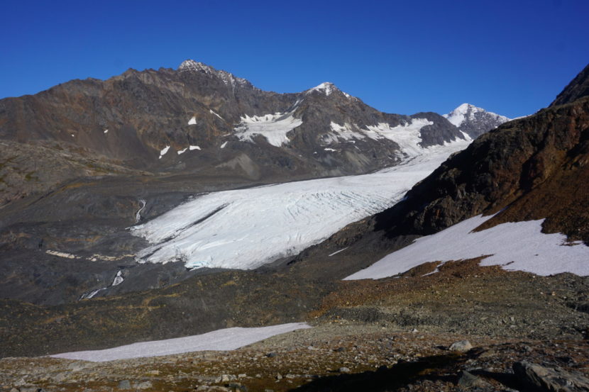 A glacier seen emerging from between two peaks.