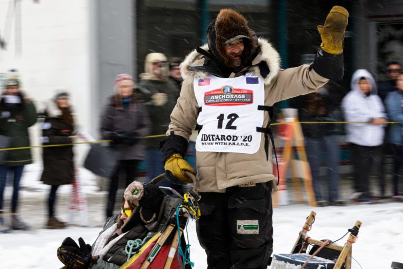 Lance Mackey waves from a dogsled