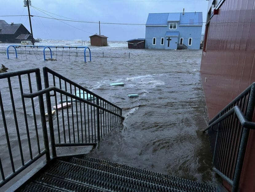 A photo from the steps of a buildings showing water inundating a community, including a church in the background