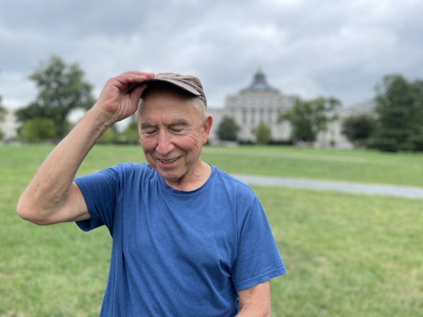A man smiling and touching the brim of his baseball cap