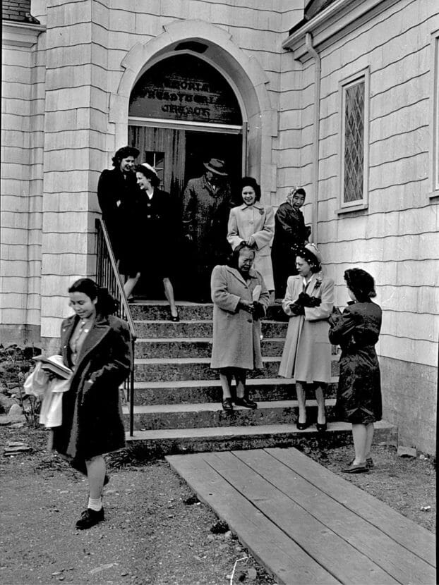 A black and white photo of people leaving a church