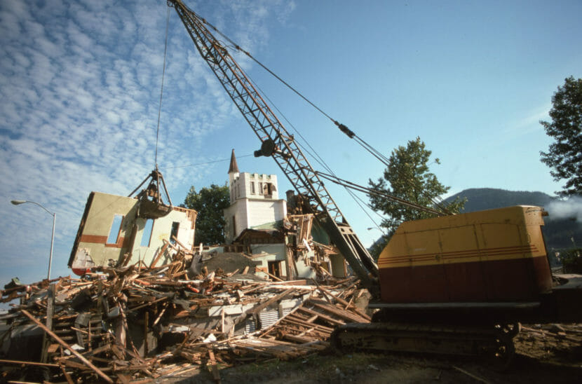 A crane lifts a wall from a building that's being demolished