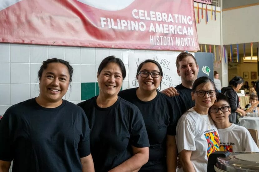 Six people pose under a "celebrating Filipino American history month" banner
