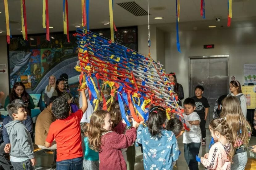Children under and around a latticework of colored streamers