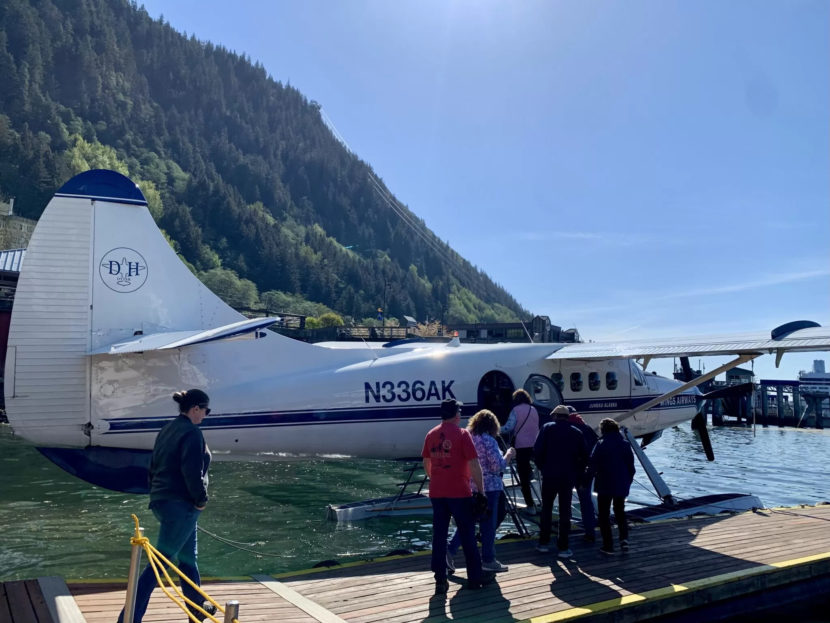 People line up on a dock to board a seaplane