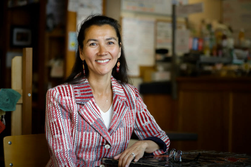 A photo portrait of Mary Peltola sitting a table and wearing a red, white and blue pinstriped blazer