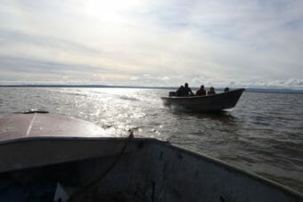 A photo taken from one skiff showing a second skiff traveling on a wide river