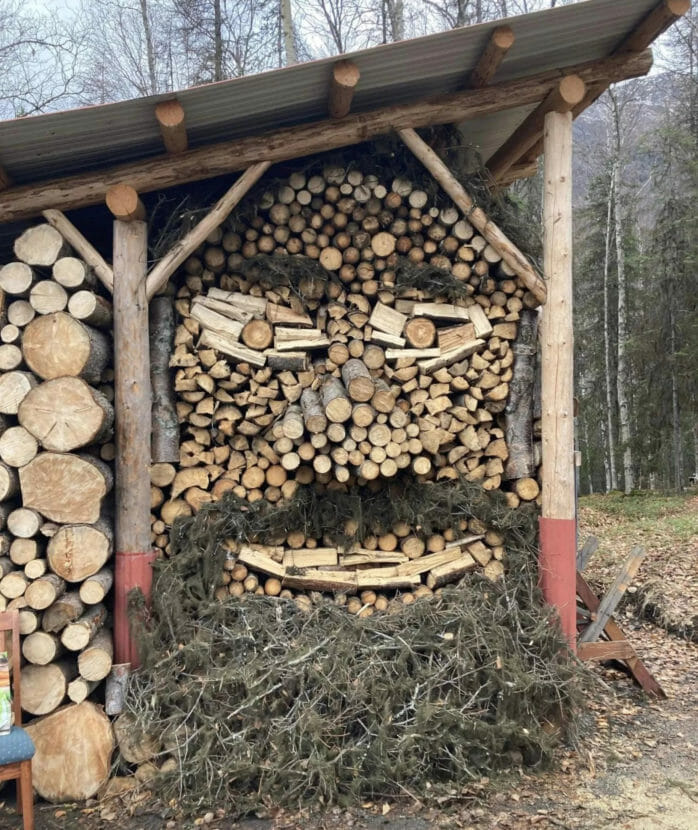 A woodpile arranged and decorated to look like a giant, bearded face