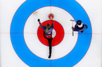 Seen from directly above, a curler gets ready to slide a stone