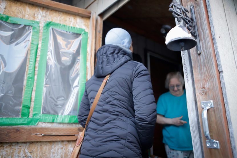 A woman stands in a doorway talking to a woman inside