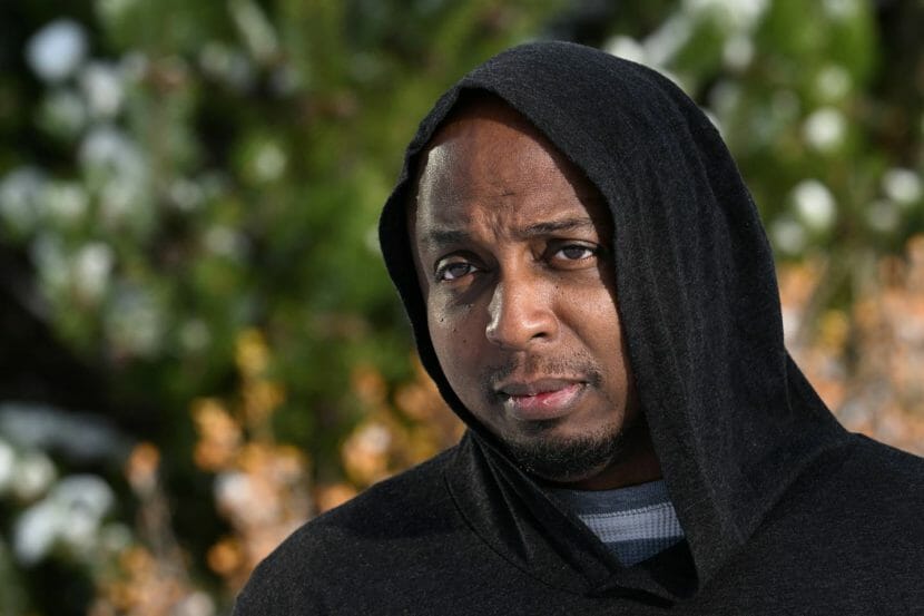 A photo portrait of a man in a black hoodie.