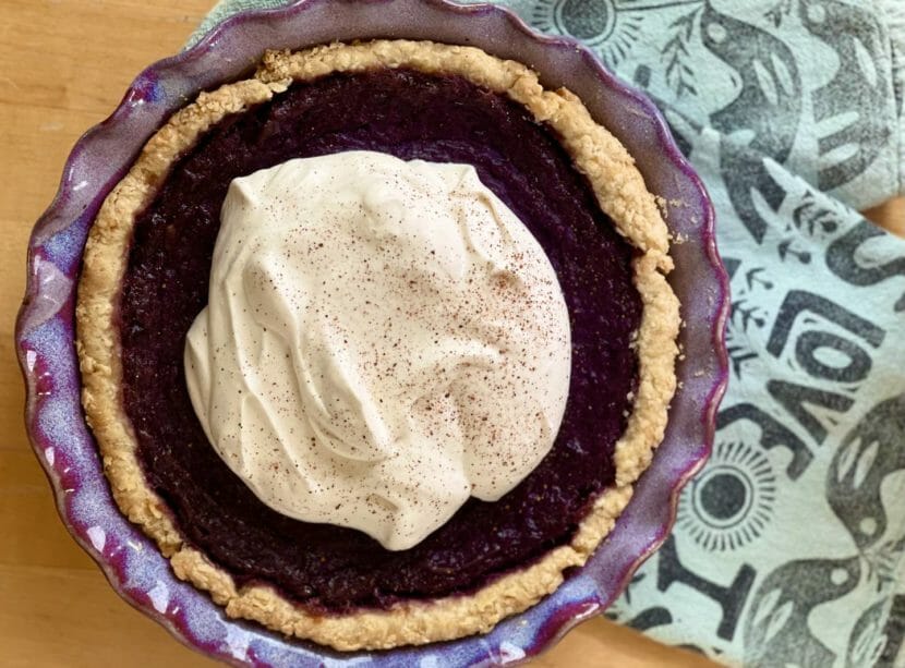 A purple pie, seen from above, with a circle of cream covering most of it