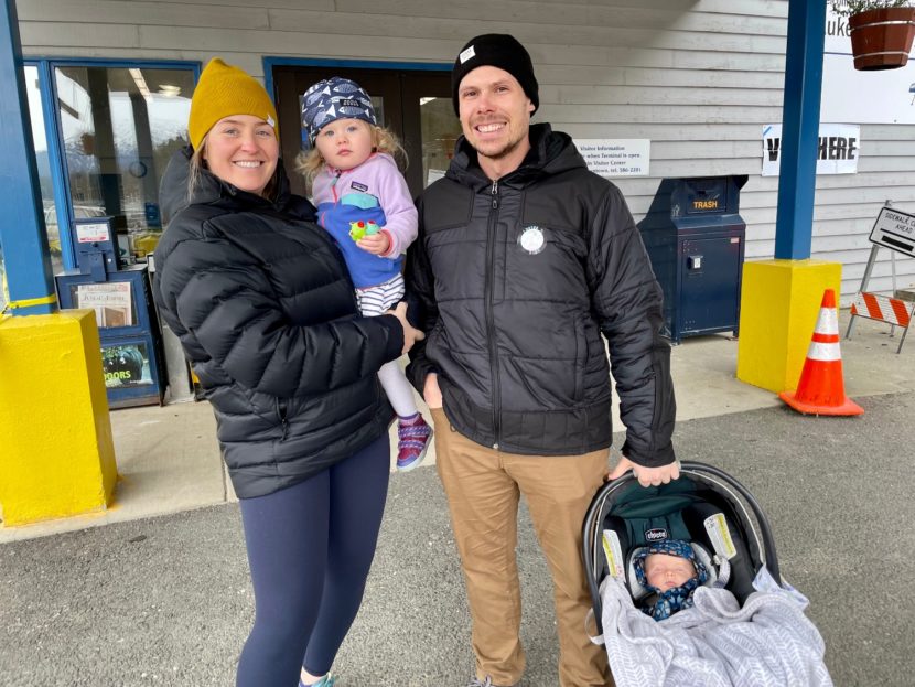 Parents with two babies stand outside a polling place