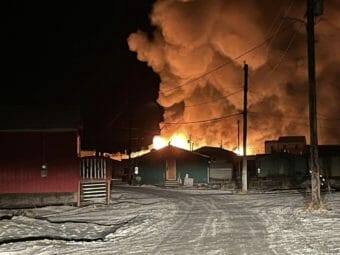 Flames and smoke above a snowy Alaska village at night.