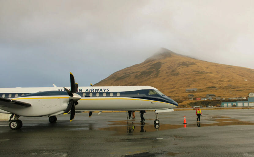 A turbo prop on the ground at the airport in Unalaska, with Mount Ballyhoo in the background.