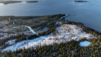 An aerial photo of a snowy, clear-cut area close to the coast.