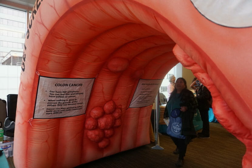 People walking through a giant inflatable colon that has inflatable tumors on it.