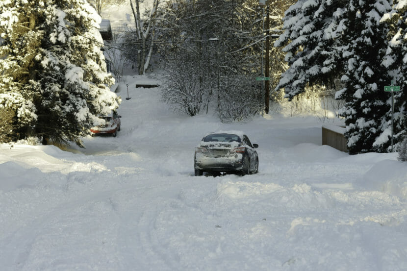 A sedan stuck in the middle of a snow-covered road.