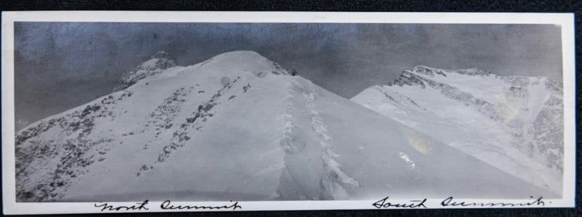 A black-and-white panoramic photo of a climber in the distance, high on a ridge on Denali