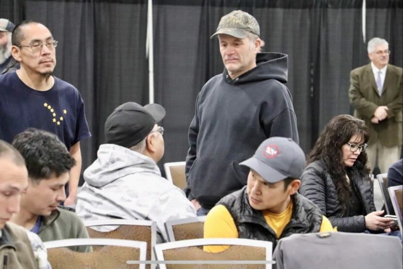 People standing and sitting at a public meeting.