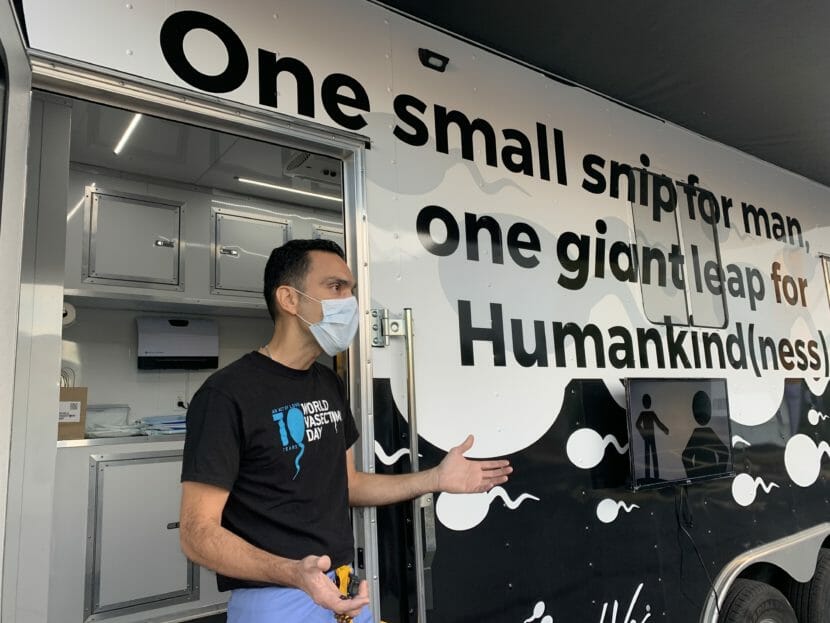 A man stands outside a large van with "one small snip for man, one giant leap for human kind(ness)" painted on the side