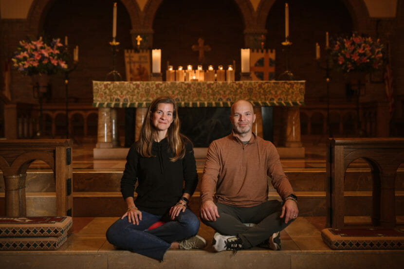 A man and a woman sit cross-legged at the front of a church.