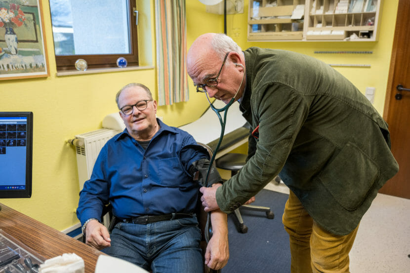 A doctor checks a man's blood pressure.