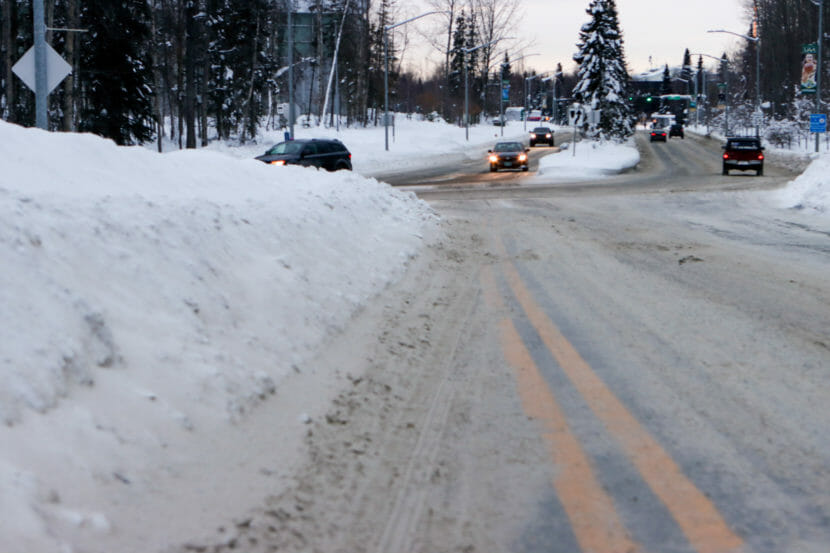 A high snow berm comes almost to the centerline of a slushy street.