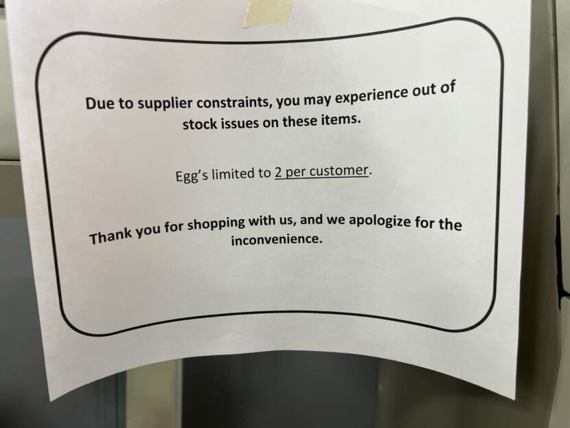 A sign on a shelf saying customers can only by two cartons of eggs each.