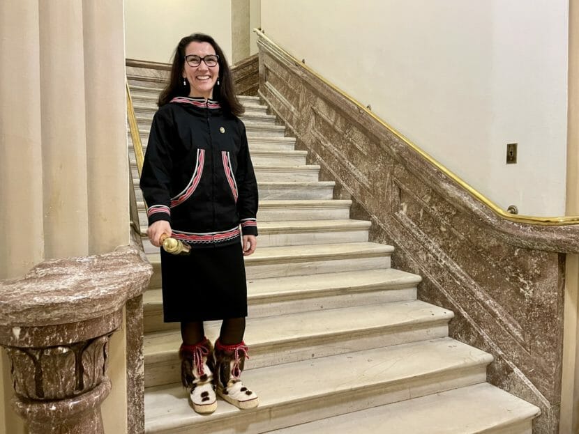wearing a kuspuk, Mary Peltola stands on an ornate stone staircase