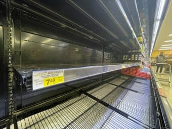 Looking down along empty refrigerated shelves in a grocery store