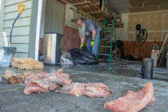 Daniel "Dune" Rothman (left) helps homeowner Sam Hatch remove wet drywall and insulation from their garage on Meander Way on Sunday August 6th following the flooding of the Mendenhall River in Saturday which brought almost a foot of water into many houses in the neighborhood. (Mikko Wilson / KTOO)