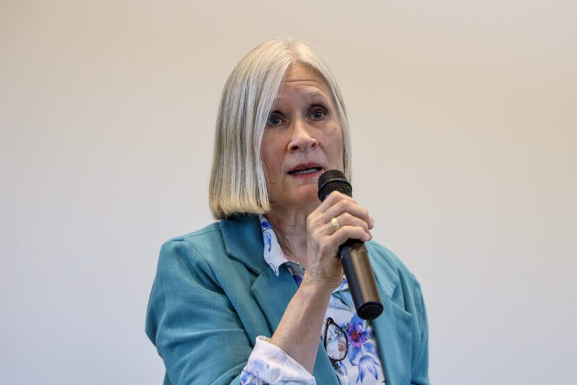 Rep. Andi Story, D-Juneau, wears a blue jacket and speaks into a black handheld microphone.