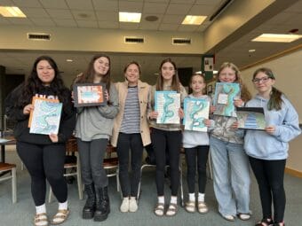 Thunder Mountain Middle School students hold up their glacial outburst flood projects beside their teacher, Jess Stanley. (Alix Soliman/KTOO)