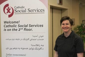 a woman with short hair stands near a sign