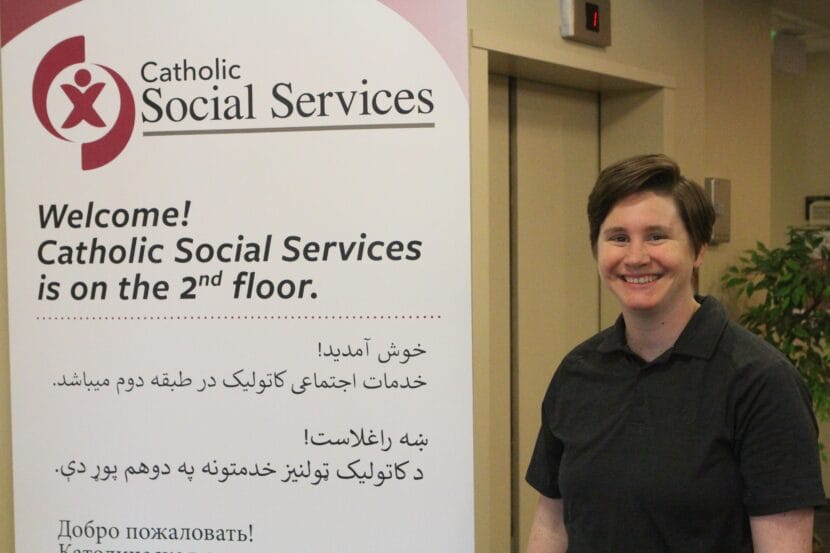 a woman with short hair stands near a sign