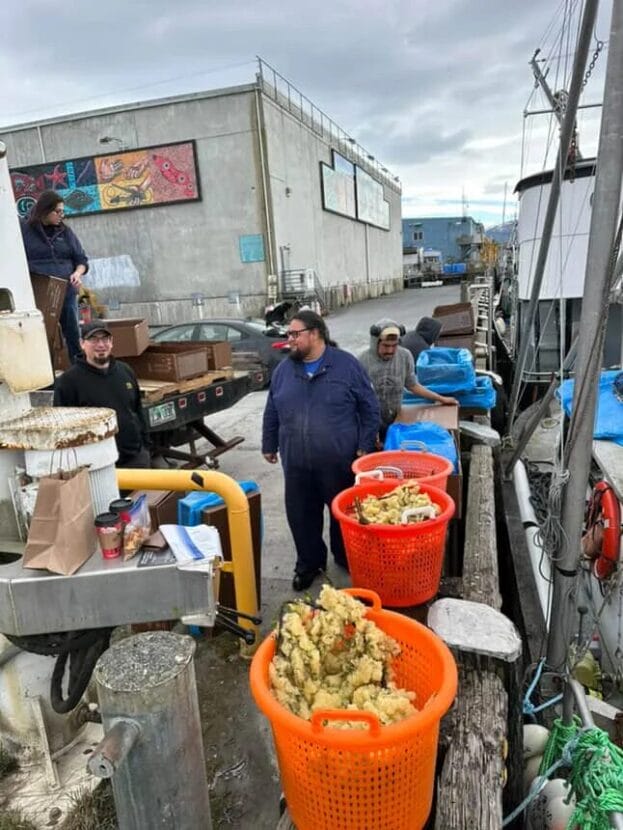 people stand along a dock surrounded by bins of herring eggs