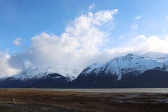 Steep, snow-covered mountains seen from across a body of water.