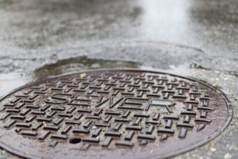 Rainwater surrounds a sewer maintenance hole in the Mendenhall Valley area in 2024. (Photo by Clarise Larson/KTOO)