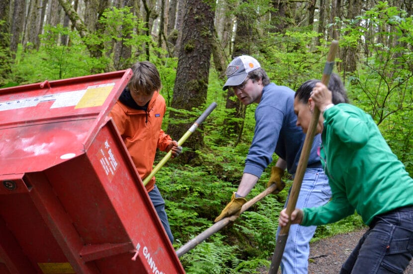 Trail Mix Inc. volunteer Henry Lloyd and two others shovel gravel out of a red motorized wheelbarrow onto the Spaulding Meadows trail on National Trails Day.