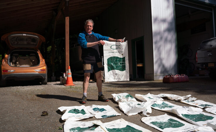 Juneau resident Wayne Carnes holds one of the 54 fish food bags he found around Funter Bay. (Photo by Alix Soliman/KTOO).