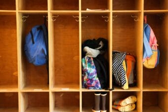 Backpacks and children's boots in wooden cubbyholes
